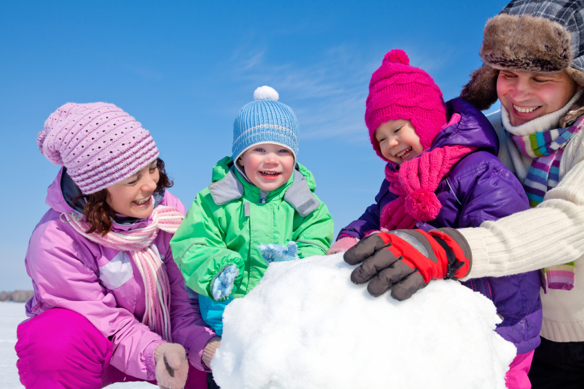 Happy couple with two children making big snowman